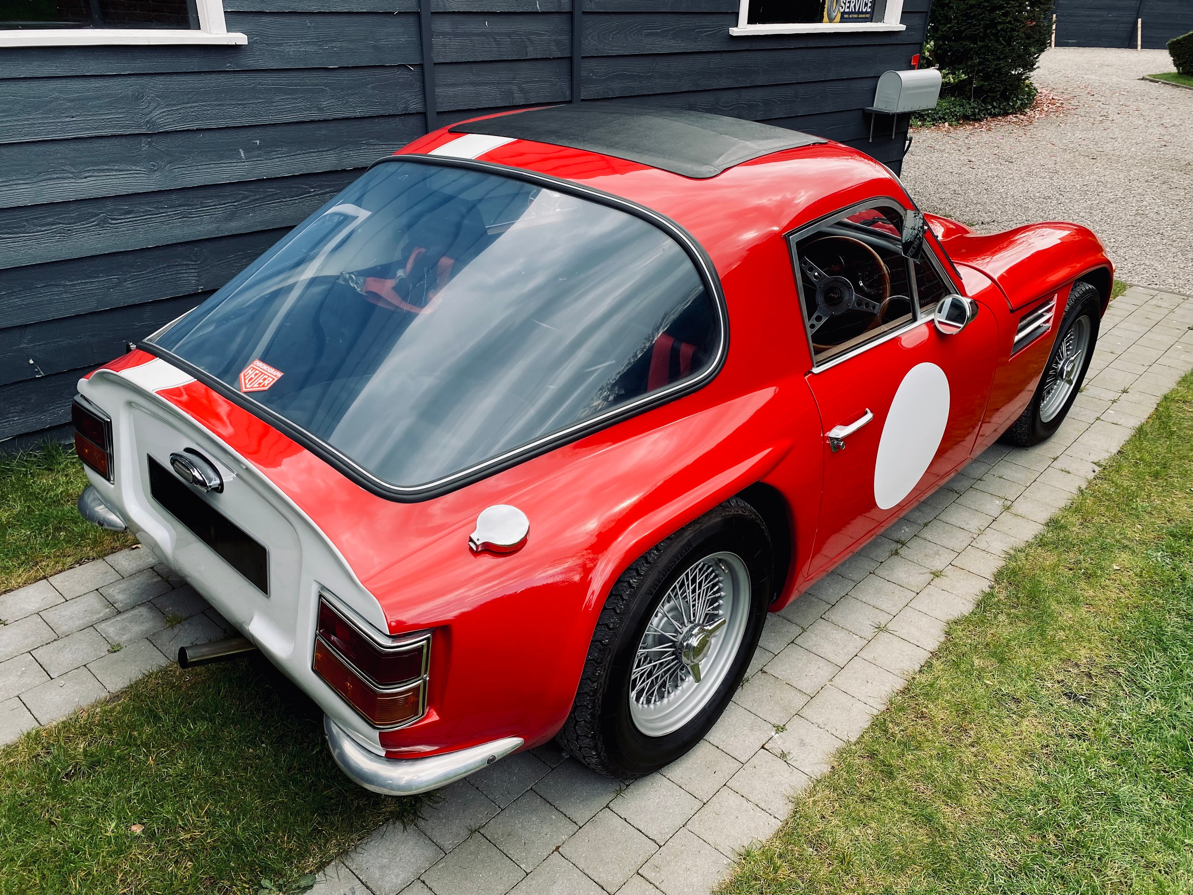 Voiture classique TVR Vixen S2 de 1969 en rouge, vue de côté, avec détails du design et des lignes élégantes.