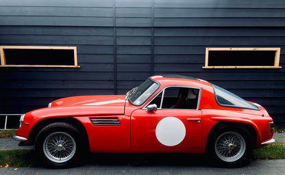 Voiture classique TVR Vixen S2 de 1969 rouge avec intérieur en cuir, vue de face dans un environnement lumineux.