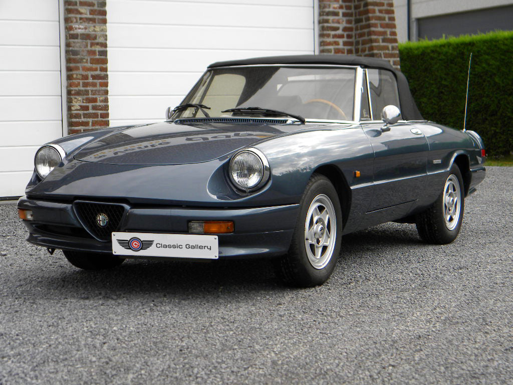 Voiture Alfa Romeo Spider 2.0 Injection essence 1989, vue de côté, avec moteur, intérieur et détails extérieurs visibles.