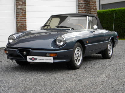 Voiture Alfa Romeo Spider 2.0 Injection essence 1989, vue de côté, avec moteur, intérieur et détails extérieurs visibles.