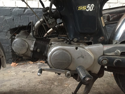 Moto Honda SS 50 cm3 année 1970, vieille moto classique avec moteur, guidon et selle visibles sur l'image.