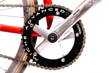 Vélo fixie Abici noir avec cadre en acier, guidon droit et pneus fins, posé sur une surface pavée.