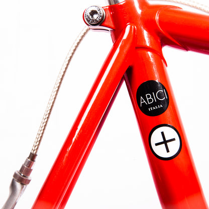 Vélo fixie Abici noir avec cadre en acier, guidon droit et pneus épais, posé sur une route urbaine.