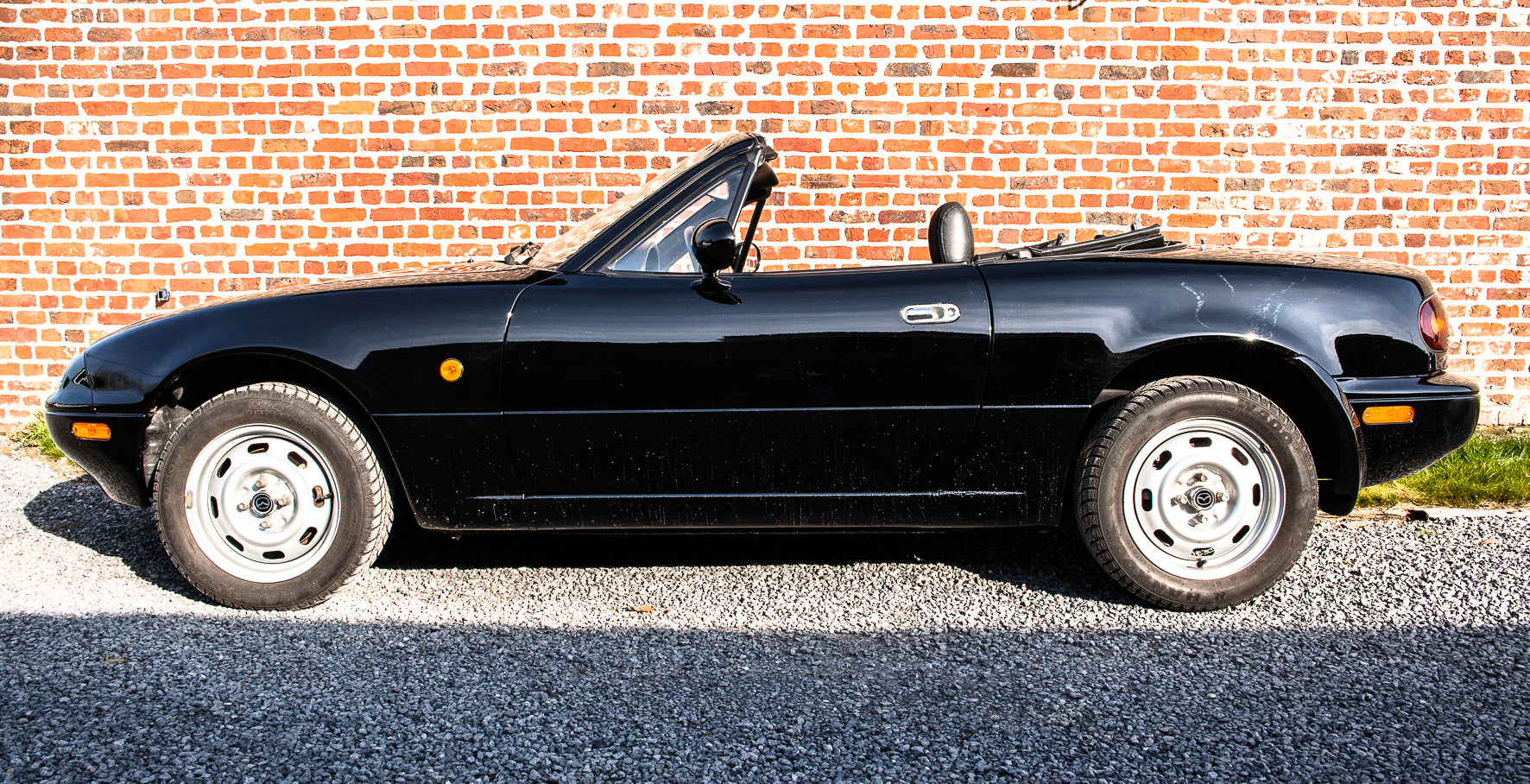 Voiture Mazda MX5 NA 1.6 essence de 1998, 105 000 km, vue de côté avec capot et roues visibles.