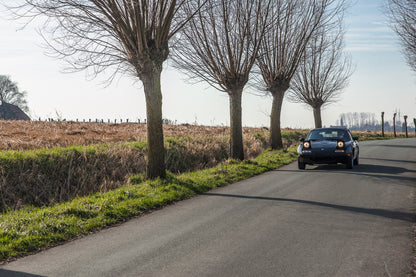 Voiture Mazda MX5 NA 1.6 essence de 1998 avec 105 000 km, vue de côté dans un environnement naturel.