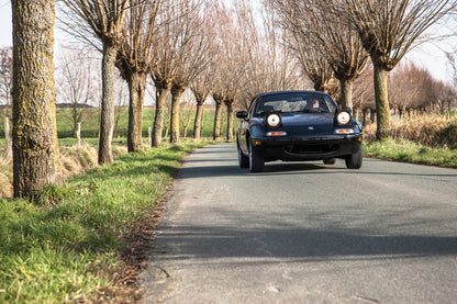 Voiture Mazda MX5 NA 1.6 essence de 1998 avec 105 000 km, vue du côté avec capot et roues visibles.